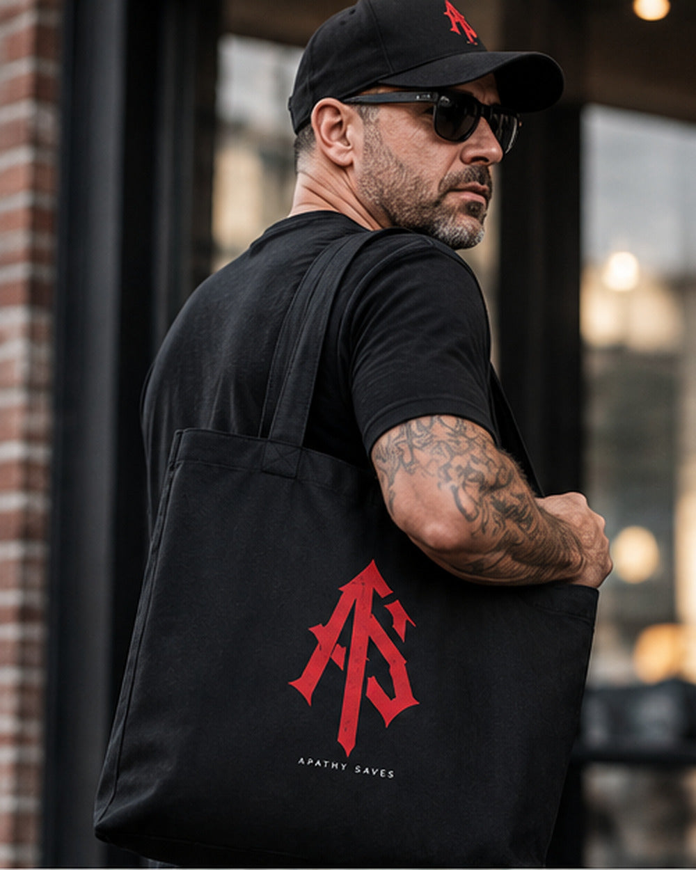 Styled lifestyle mockup of a man carrying the black ApathySaves AS monogram tote over his shoulder