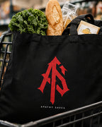 Styled lifestyle mockup of the black ApathySaves organic cotton tote carrying groceries