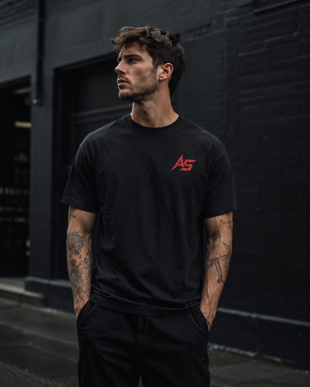 Male model wearing black ApathySaves t-shirt with small red AS logo on front chest