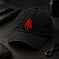 Black ApathySaves unstructured cotton dad hat with red interlocking AS embroidery, styled on a dark editorial flat lay